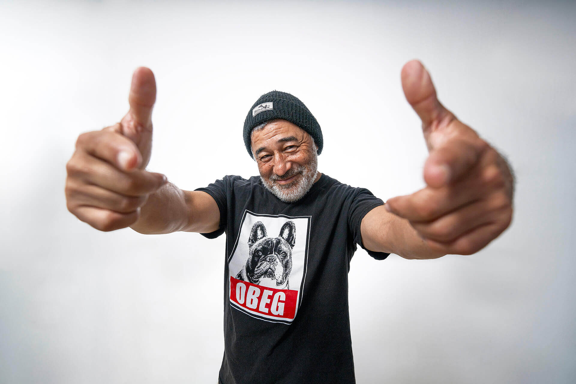Steve Caballero extending both thumbs toward the camera against a light background.