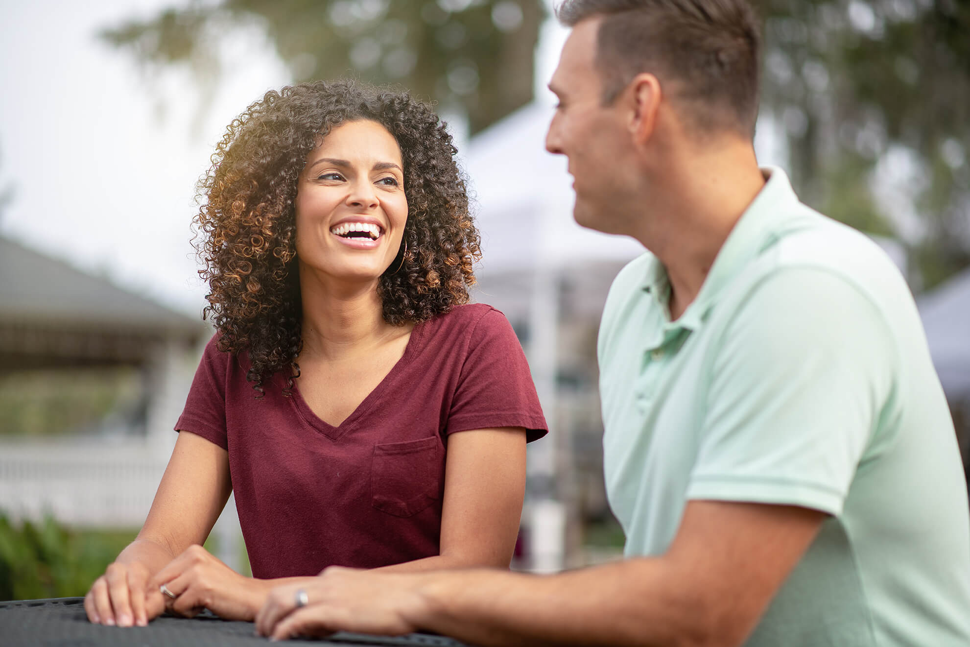 Two people smiling and talking together outdoors.