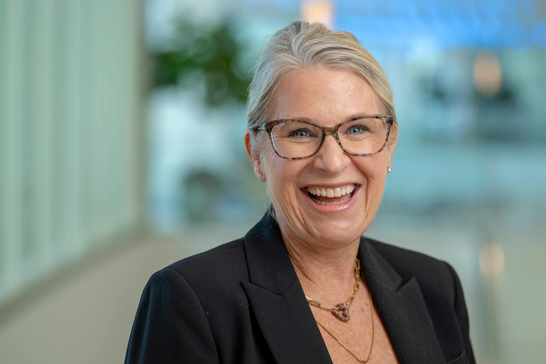 Smiling woman with glasses photographed in a bright office interior.