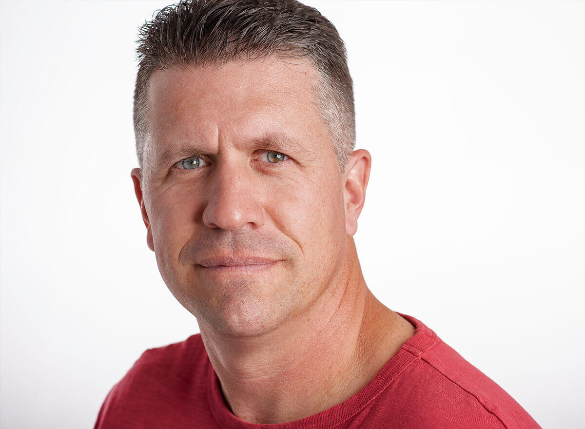 Man in a red shirt photographed against a clean white background.